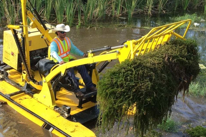 Worker removing debris from a pond - Irrigation specialists Sorko Services in Sanford, FL 
